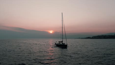 Barco-Solitario-Navegando-En-El-Mar-En-Calma-Durante-La-Puesta-De-Sol-En-Génova,-Italia---Tiro-Ancho