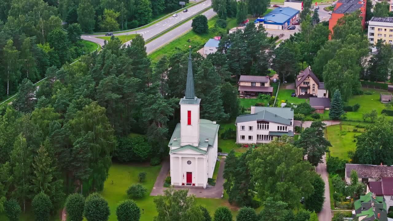 Ikšķile Lutheran church seen from above with active road in green summer forest