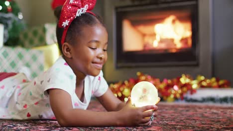 Glückliches-Afroamerikanisches-Mädchen,-Das-Mit-Einer-Schneekugel-Spielt