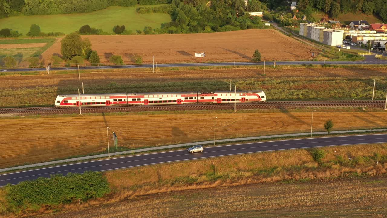 해가 지는 시골 풍경 에 있는 빨간색 전기 열차 - 공중 촬영