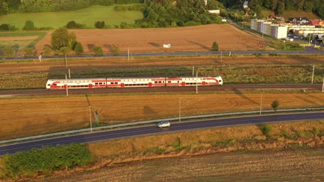 Tren-Eléctrico-Rojo-En-El-Paisaje-Rural-Al-Atardecer---Toma-Aérea