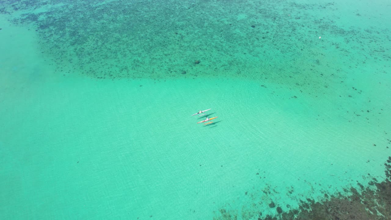 2 Kayakers paddling along in tropical waters next to the vibrant reef