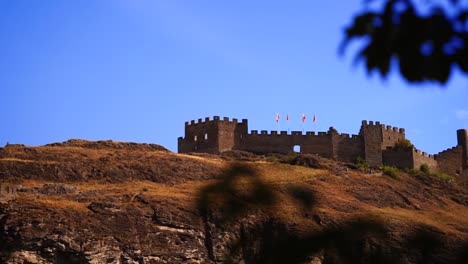 Reveal-shot-of-Chateau-de-Tourbillon-epic-fortress-wall-on-hill-in-Swiss-Alps