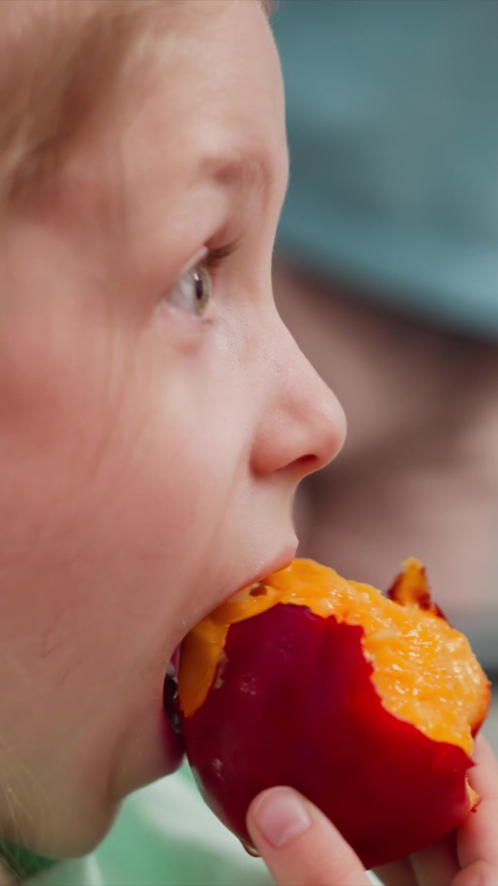Close up of young girl eating fruit focusing on her profile as girl takes bites from orange. sequence captures texture and color of both child skin and juicy interior of peeled red orange