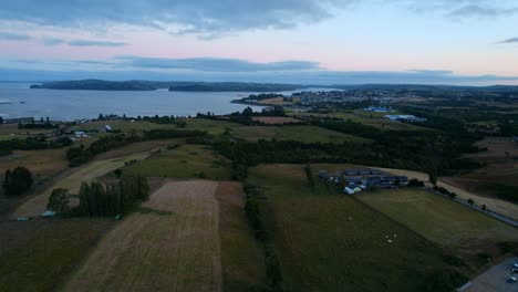 Drone-establishing-shot-in-a-lonely-meadow-in-an-orange-and-bluish-sunset-with-clouds