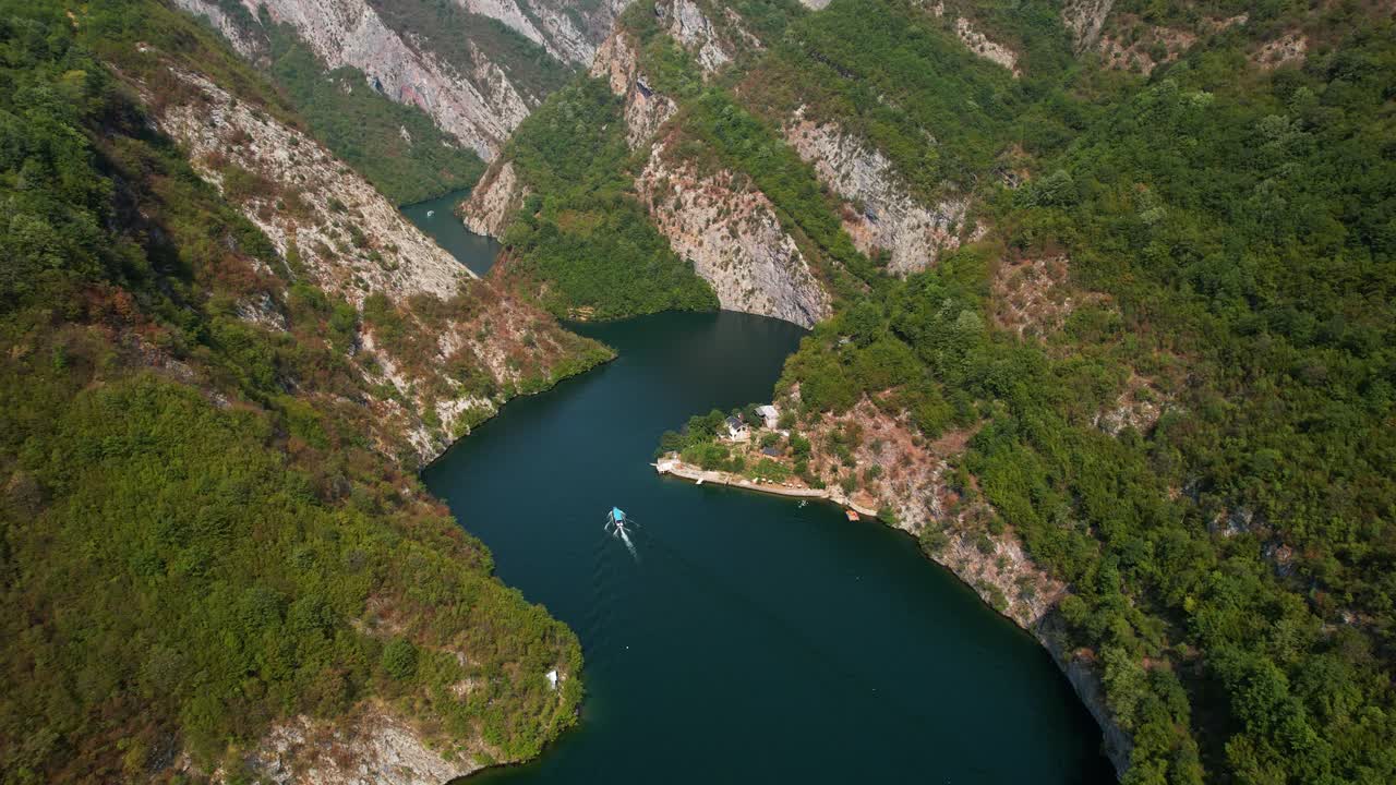 알바니아의 아름다운 강 계곡을 가로질러 항해하는 관광 보트와 함께 평온한 산 호수에 반사되는 바위 산