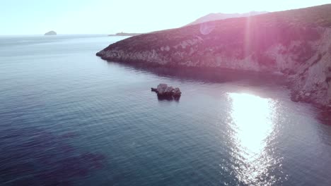 scenic aerial view of sea rock formation in secluded bay, peaceful water, sunset