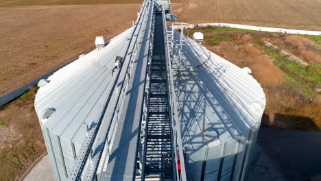 modern granary in a sunny daytime. metal construction on the top of grain elevator on field background. top aerial view.