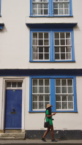 vertical video of female tourist with camera on vacation in oxford uk exploring city walking along holywell street using mobile phone for directions and information