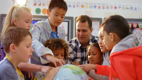 front view of caucasian male teacher teaching the kids about the globe in the classroom 4k