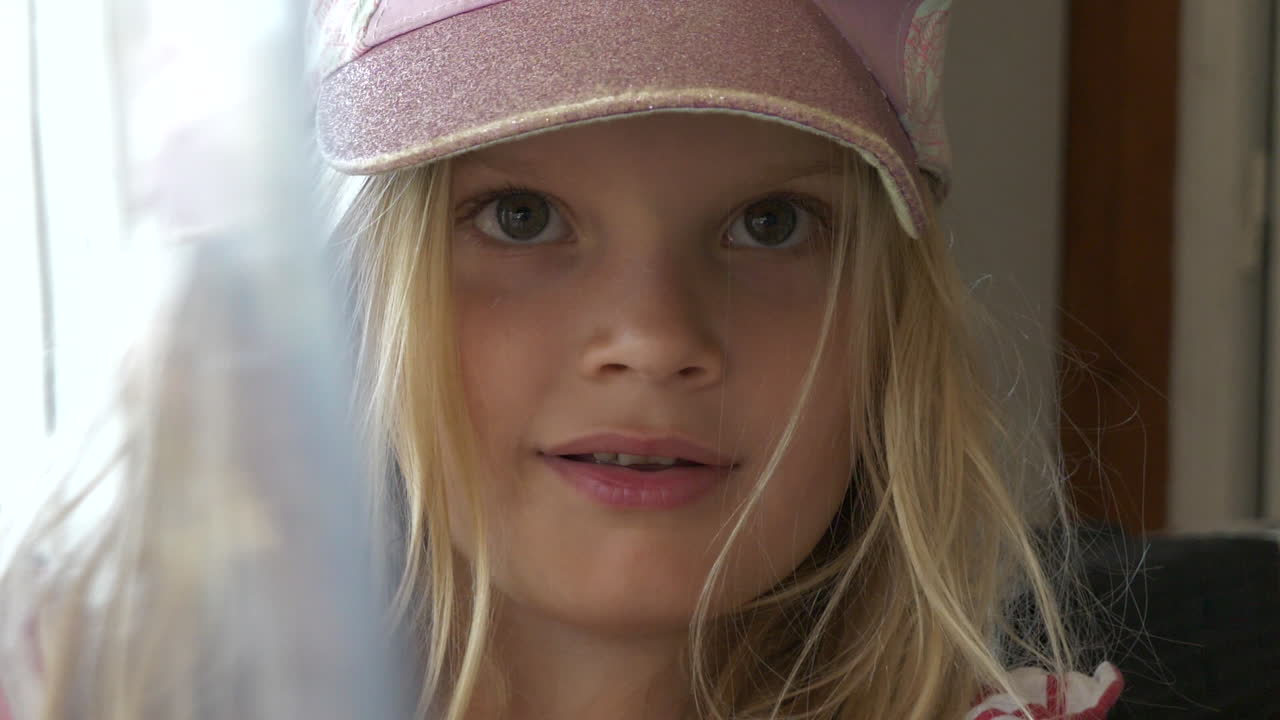 крупный план молодой светловолосой девушки в кепке, которая слушает, а затем улыбается и смеется