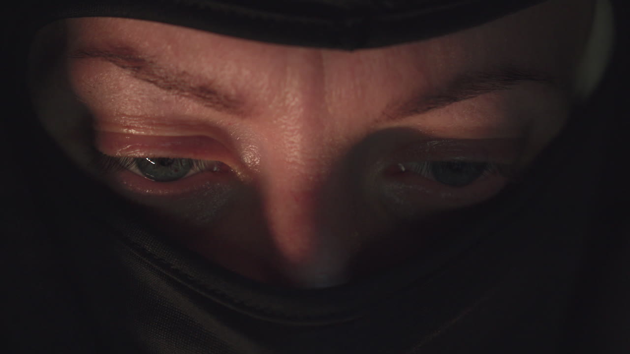 ojos de ladrón enmascarado mirando la pantalla de la computadora en una habitación oscura