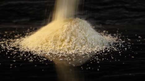 close up of white grated coconut in a small pile with reflection and dark background