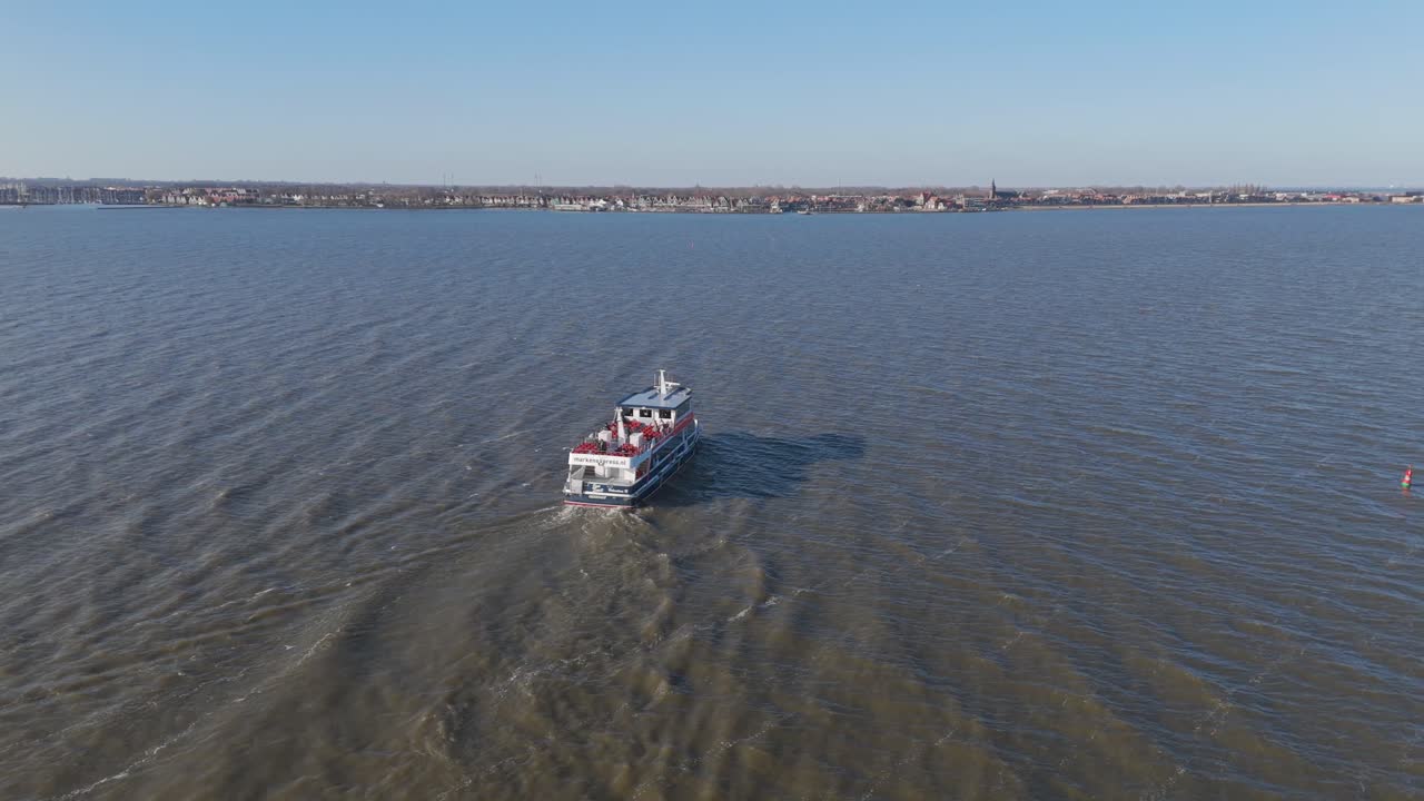 Luchtopnamen met drone van een toeristenboot die vaart op het Markermeer bij Volendam, Nederland, met kalm water en een schilderachtige Nederlandse kustlijn.
