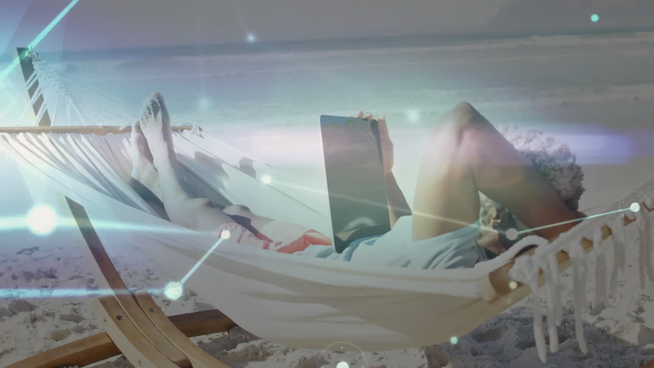 Person relaxing in hammock on beach with digital network animation overlay
