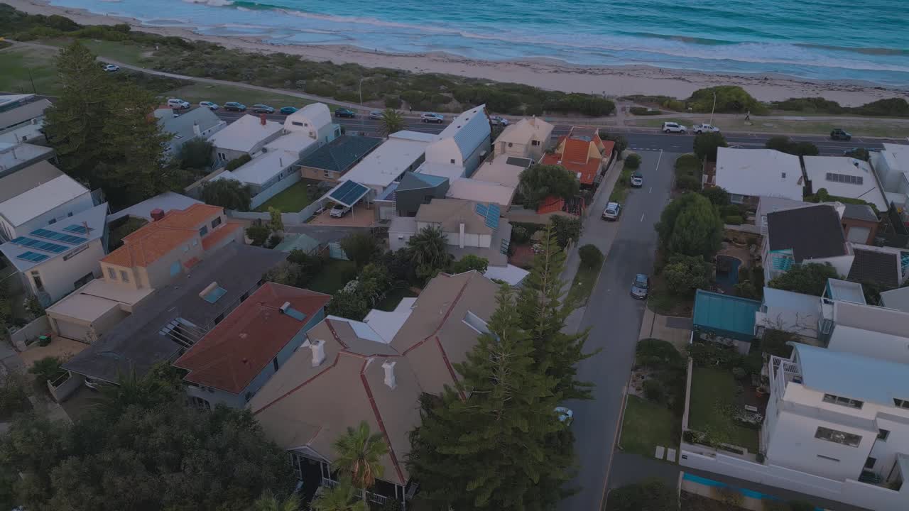 Drone Footage overseeing a cluster of houses next to the Cottesloe Beach in Perth, Western Australia. The footage advances towards the sandy beach and Indian Ocean
