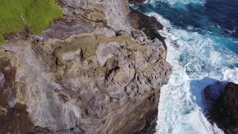 Hermosas-Olas-Azules-Rompiendo-En-La-Cueva-De-Escupir-En-Honolulu-Hawaii-Con-Acantilados-Irregulares-Y-Vegetación-Vibrante---Muñeca-Aérea-De-Arriba-Hacia-Abajo