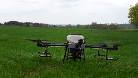 Agriculture-Drone-With-Empty-Tank-For-Fertilizer-Landing-on-Green-Farming-Field,-Slow-Motion