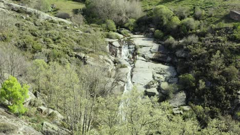 Vuelo-Inverso-Con-Un-Dron-En-La-Ladera-De-Una-Montaña-Donde-El-Curso-De-Un-Caudaloso-Arroyo-Pasa-Sobre-Un-Gran-Barco-De-Granito.