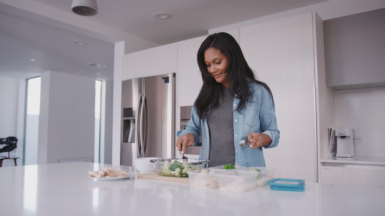 Donna in cucina che prepara un pasto ad alto contenuto proteico e mette le porzioni in contenitori di plastica