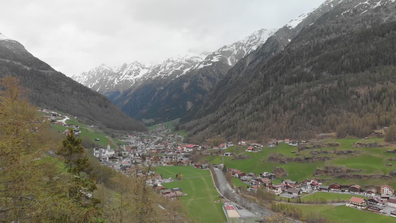 disparo de drones pasando en medio de un telecabina que revela un pequeño pueblo en los alpes austriacos - sölden, austria