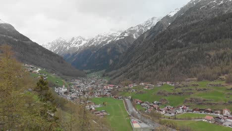 disparo de drones pasando en medio de un telecabina que revela un pequeño pueblo en los alpes austriacos - sölden, austria