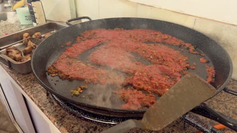 persona está mezclando el contenido de la placa de la sartén metálica, preparando y cocinando el concepto de alimentos