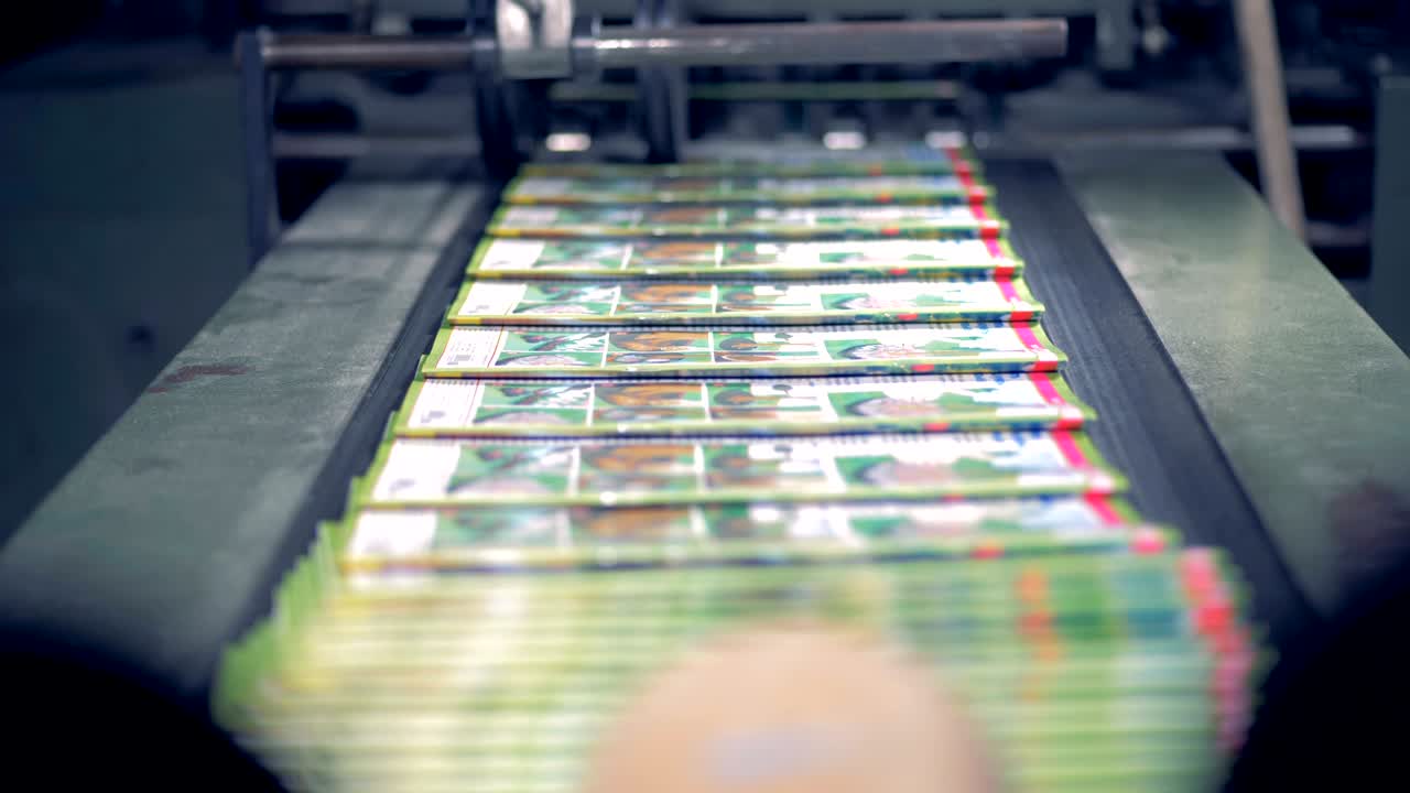 las revistas están siendo lanzadas por una máquina tipográfica, apiladas y guardadas por un empleado