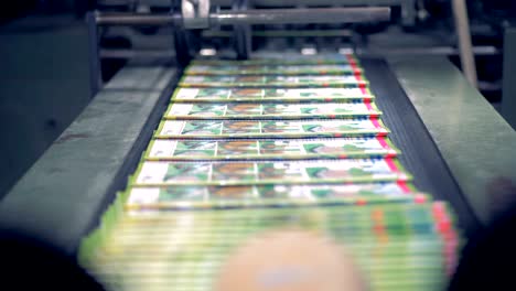 las revistas están siendo lanzadas por una máquina tipográfica, apiladas y guardadas por un empleado