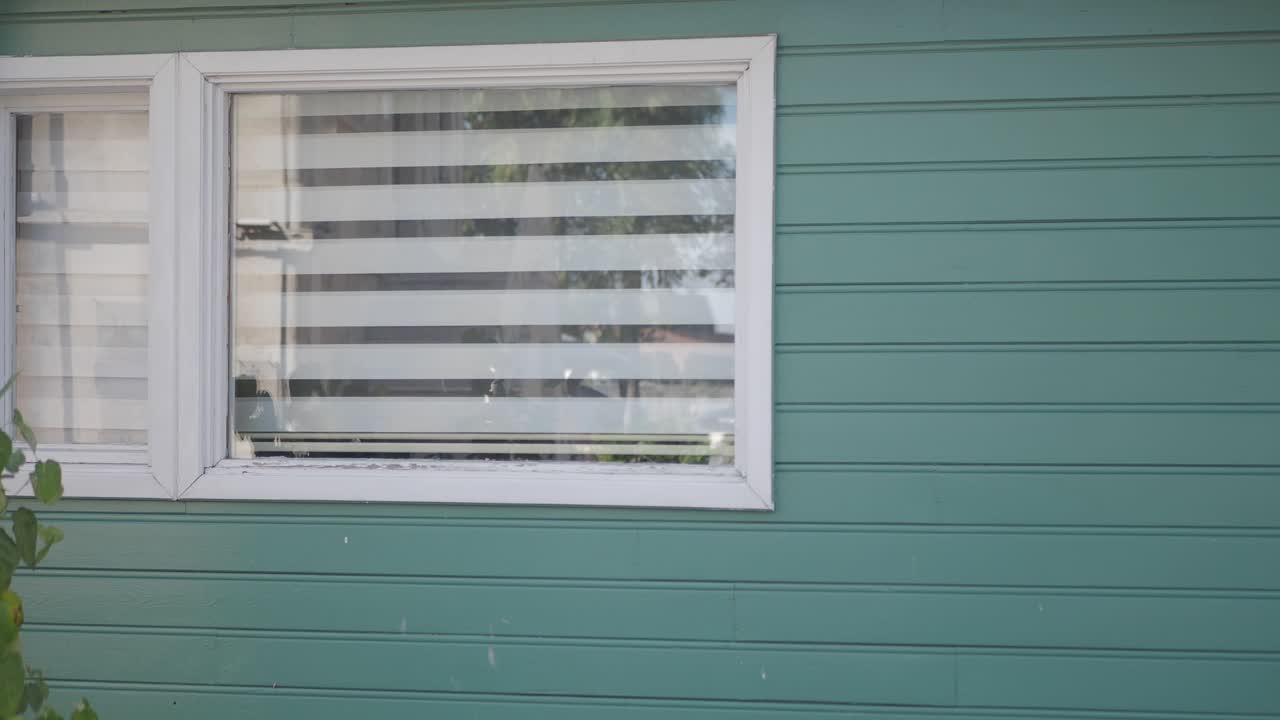 Außenansicht eines grünen Hauses mit Fenster und Jalousien