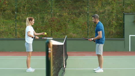 Seitenansicht-Eines-Glücklichen-Paares,-Das-An-Einem-Sommertag-Auf-Dem-Außenplatz-Tennis-Spielt