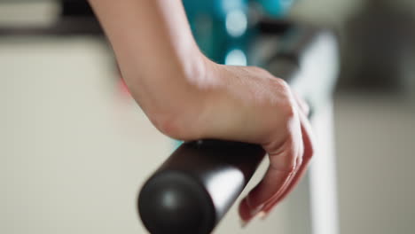 woman moves fingers over treadmill handlebar closeup. athlete takes break after run leaning on handlebar in fitness club. wellness sport way of life