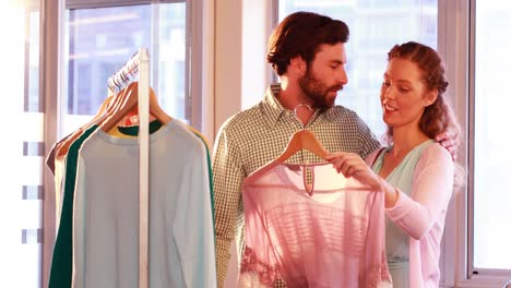 Couple-selecting-a-dress-while-shopping-for-clothes