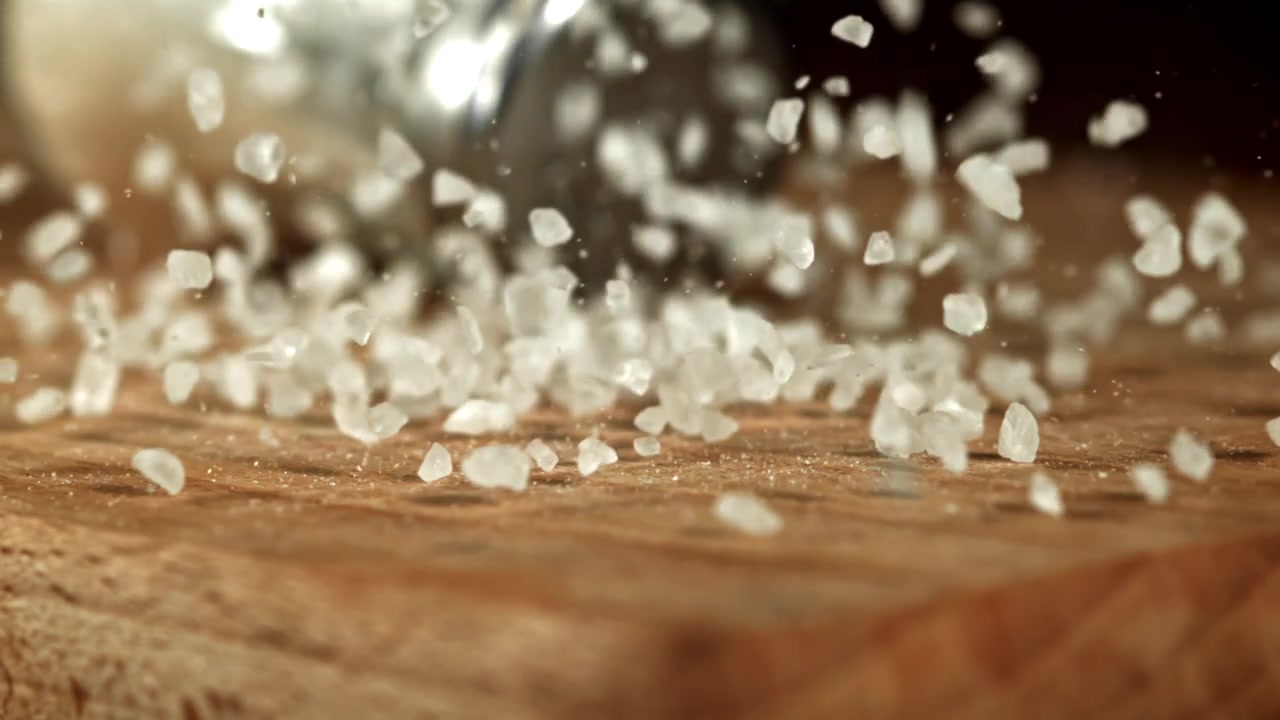 Sale che cade al rallentatore da una saliera su una superficie di legno