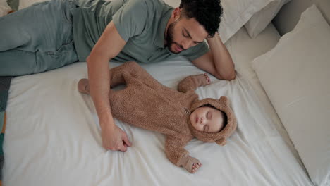 un padre mira con amor a su bebé durmiendo