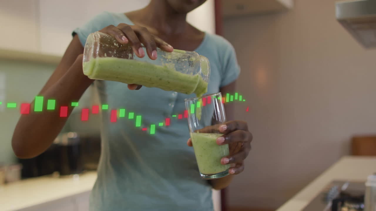 Pouring green smoothie into glass, financial stock market animation in kitchen