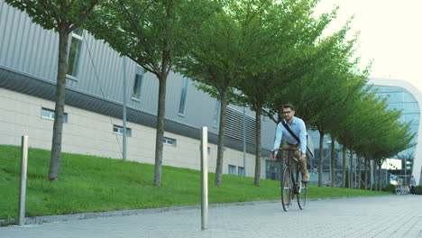 young caucasian stylish man in glasses riding a bike in the city