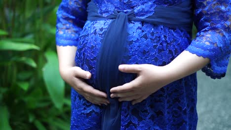 pregnant woman touching her belly in the garden