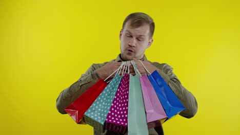 man showing black friday inscription on shopping bags, smiling, satisfied with low prices purchases