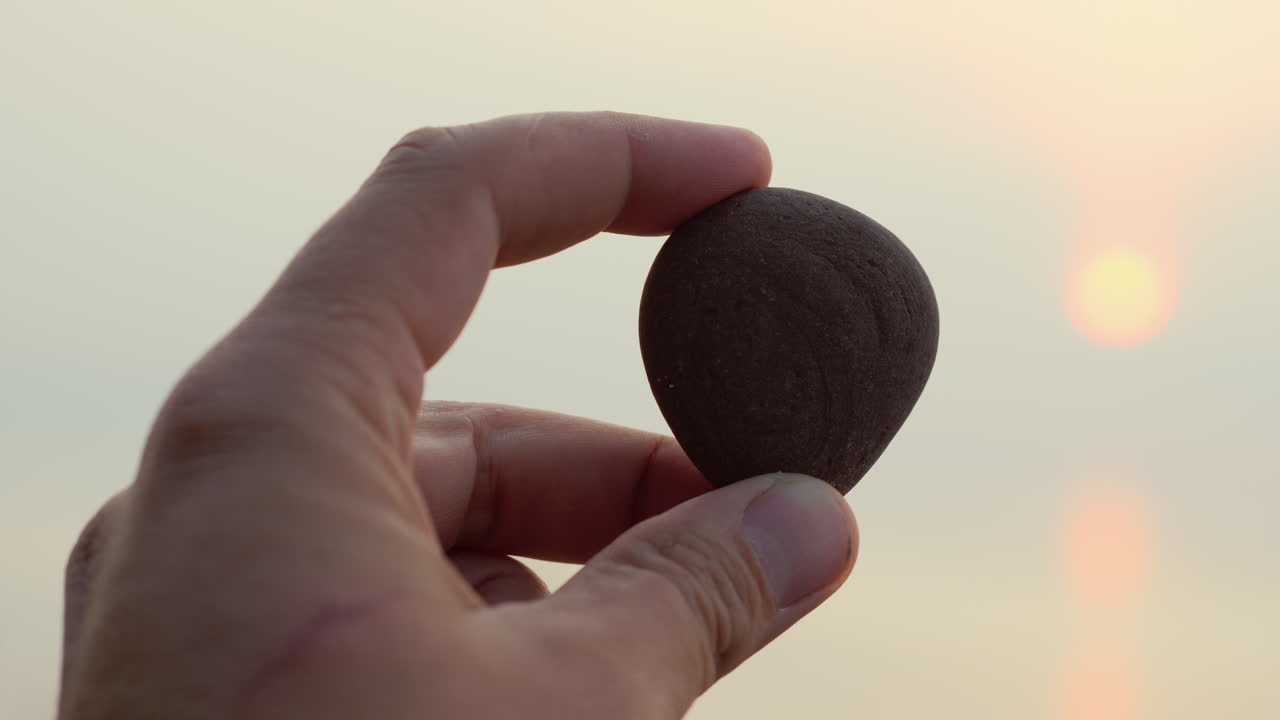 손은 바다와 태양의 배경에 자갈을 보유