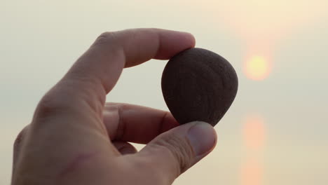 hand holds pebbles on a background of sea and sun