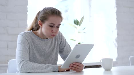mujer joven reaccionando a la pérdida financiera mientras usa la tableta