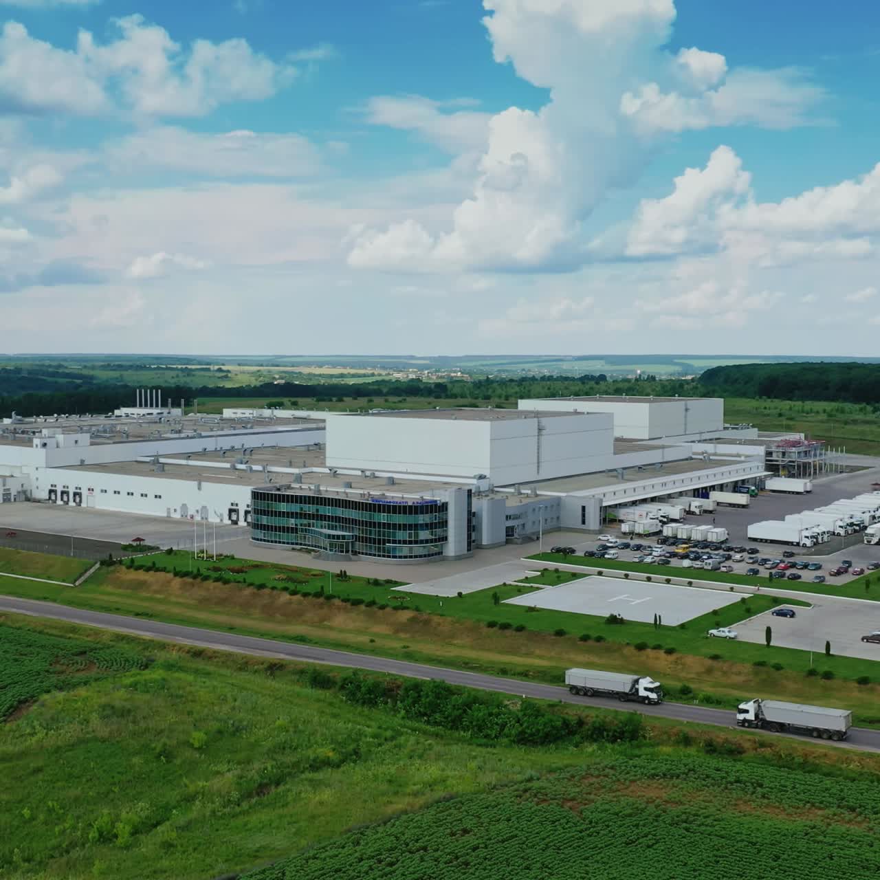 Modern plant in the countryside. Panoramic view on industrial area among green nature. Large manufacture on field in summer.