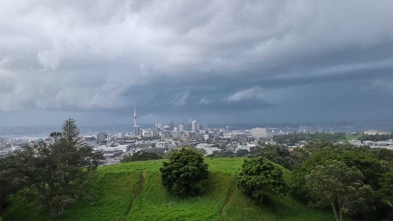 공원에서 오클랜드 시 위로 오는 폭풍을 바라보고 있습니다.