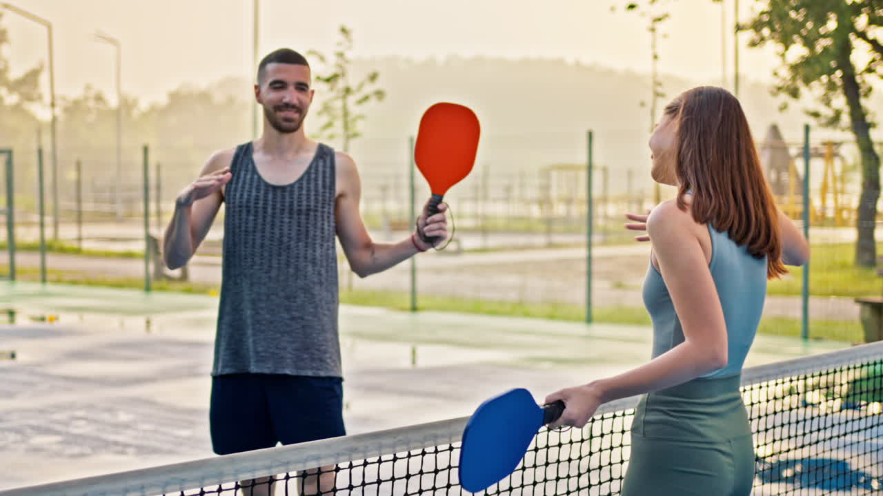 A man and a woman playing pickleball after rain