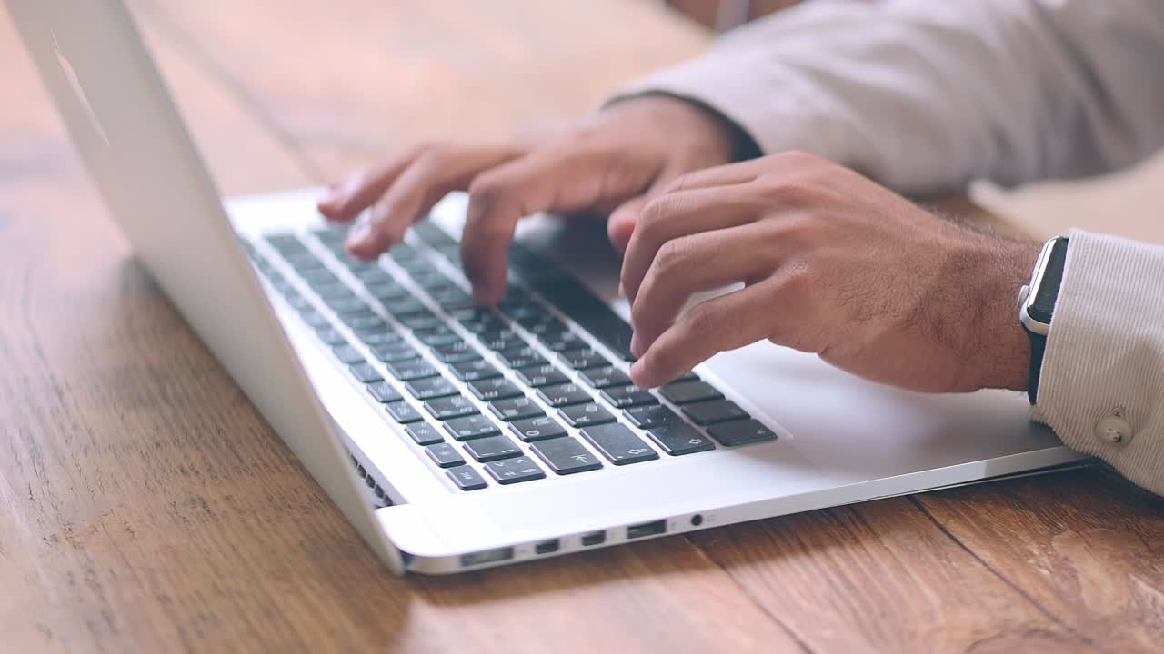 Man hands typing on keyboard of silver laptop performing work of secretary