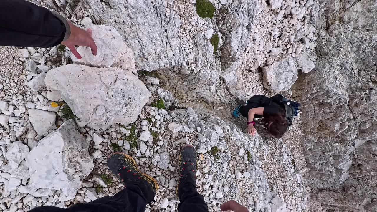 Widok POV z wędrówki przez Przełęcz Santner, po nierównych wapiennych głazach i wąskim alpejskim szlaku górskim.