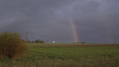 Hermoso-Paisaje-Nocturno-De-Un-Campo-Verde-Con-Un-Arco-Iris-Antes-De-La-Lluvia