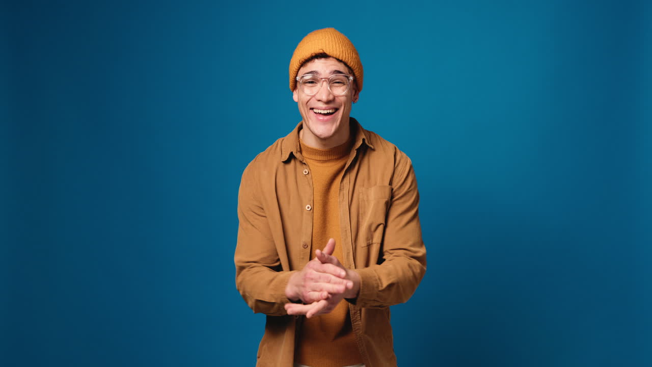 Man in beanie and glasses pointing and smiling
