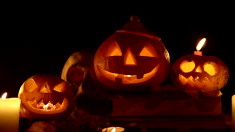 candle with flickering light and group of pumpkins at the table